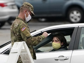 A member of the National Guard assisting at a COVID-19 mobile testing location fills out paperwork for a motorist arriving for a test Dec. 1, 2020, in Auburn, Maine.