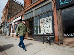 A closed storefront boutique business displays a sign pleading for help during the COVID-19 pandemic, in Toronto in April 2020.