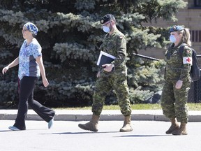 A staff member escorts members of the Canadian Armed Forces in to a long term care home, in Pickering, Ont. on Saturday, April 25, 2020.