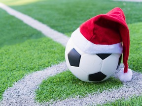 Santa Claus red hat on soccer ball at green grass