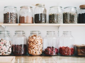 Organic bulk products in zero waste shop. Foods storage in kitchen at low waste lifestyle. Dried berries and fruits in glass jars on shelves. Eco friendly shopping in plastic free grocery store.