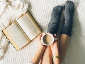woman laying in bed and read book with cup if coffee.