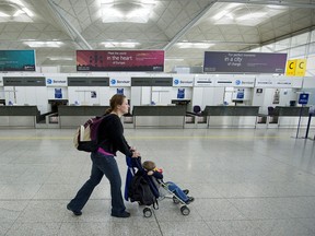 A woman pushes a child's stroller past empty check-in desks at Stansted Airport in Essex, eastern England.