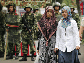Two Uighur women pass Chinese paramilitary policemen standing guard outside the Grand Bazaar in the Uighur district of the city of Urumqi.