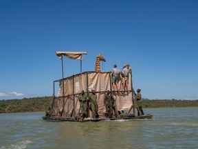 Rescue team members stand on the barge as Asiwa a Rothschild's (Nubian) giraffe which was stranded on the Longicharo Island, a rocky lava pinnacle, is moved off the flooded island on Lake Baringo, Kenya December 2, 2020.