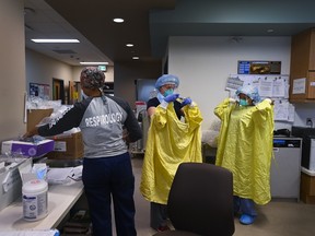 ICU health-care workers don PPE before entering a negative pressure room to care for a COVID-19 patient on a ventilator at the Humber River Hospital during the COVID-19 pandemic in Toronto on Wednesday, December 9, 2020.