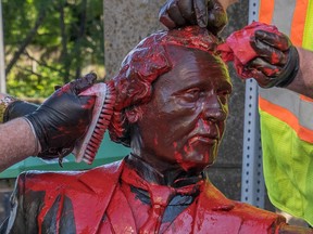 Workers remove red paint from a statue of Sir John A. Macdonald in Charlottetown on June 19, 2020.