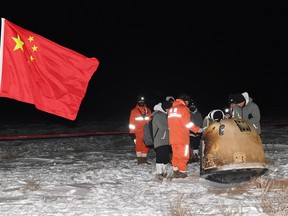 Researchers work around Chang'e-5 lunar return capsule carrying moon samples next to a Chinese national flag, after it landed in northern China's Inner Mongolia Autonomous Region, December 17, 2020.