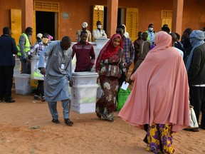 Electoral commission officials carry ballot boxes outside a polling station in Niamey on December 27, 2020 during Niger's presidential and legislative elections.