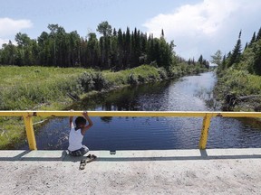 A boy from the Shoal Lake 40 First Nation sits on a bridge over a channel on on Thursday, June 25, 2015.