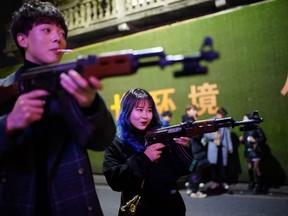 People play with toy guns outside a bar at night, almost a year after the global outbreak of the coronavirus disease in Wuhan, Hubei province, China, Dec. 11, 2020.