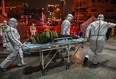 Medical staff members wearing protective clothing arrive with a patient at the Wuhan Red Cross Hospital in Wuhan on January 25, 2020.