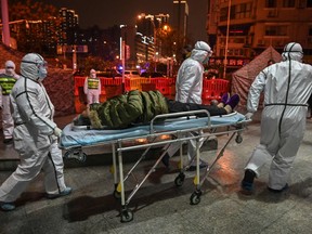 Medical staff members wearing protective clothing arrive with a patient at the Wuhan Red Cross Hospital in Wuhan on January 25, 2020.