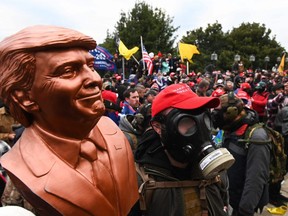 A supporter of U.S. President Donald Trump wears a gas mask and holds a bust of him after he and hundreds of others stormed stormed the Capitol building on January 6, 2021 in Washington, DC.