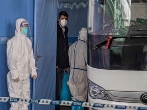 Vladimir G. Dedkov (C), a member of the World Health Organization (WHO) team investigating the origins of the Covid-19 pandemic, boards a bus following the team's arrival at a cordoned-off section in the international arrivals area at the airport in Wuhan on January 14, 2021.