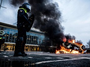 A car has been set on fire in front of the train station, on January 24, 2021 in Eindhoven, after a rally by several hundreds of people against the corona policy.