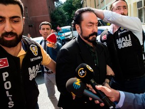 Turkish police officers escort televangelist and leader of a sect, Adnan Oktar (C) on July 11, 2018, in Istanbul, as he is detained on fraud charges.  Turkish police detained the televangelist on fraud charges on July 11, 2018, notorious for propagating conservative views while surrounded by scantily-clad women he refers to as his "kittens".