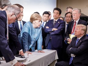 U.S. President Donald Trump, right, talking with German Chancellor Angela Merkel, centre, and surrounded by other G7 leaders during a meeting of the G7 Summit in La Malbaie, Quebec, Canada on June 9, 2018.