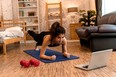 20s young Asian woman in sportswear doing plank poses while watching fitness training class on computer laptop online. Healthy girl exercising and learning in bed room. Internet education concept.