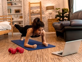 20s young Asian woman in sportswear doing plank poses while watching fitness training class on computer laptop online. Healthy girl exercising and learning in bed room. Internet education concept.