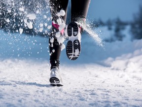 Athlete woman is running during winter training outside in cold snow weather.