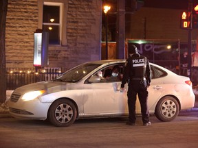 Police ticket a vehicle as they enforce a night curfew imposed by the Quebec government to help slow the spread of COVID-19 in Montreal, on Jan. 9.