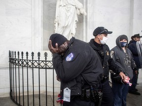 A member of the Capitol Police force covers his face as Trump protesters storm the U.S. Capitol Building in Washington, D.C., to contest the result of the presidential election, on Jan. 6, 2021.