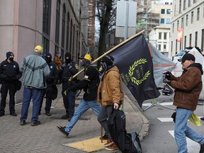 Members of the Proud Boys walk past law enforcement officers near the Virginia State Capitol on Lobby Day, a day traditionally set aside for the public to lobby lawmakers, in Richmond, Va., on Jan. 18, 2021.