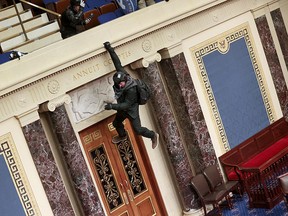 A protester is seen hanging from the balcony as pro-Trump protesters breach the U.S. Senate chamber in Washington on January 6, 2021.