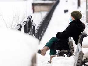 A woman sits next to the Lachine Canal in Montreal on Jan. 17, 2021, during the COVID-19 lockdown and curfew in Quebec.