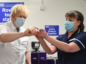 British Prime Minister Boris Johnson is shown the Oxford/AstraZeneca COVID-19 vaccine with nurse Tracey Wilkinson at Barnet FC's ground at The Hive, which is being used as a vaccination centre on Jan. 25, 2021 in London, England.