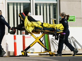 A patient in wheeled into a hospital by ambulance workers in Montreal, on Monday, January 18, 2021.