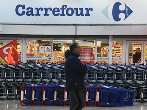 In this file photo taken on March 30, 2018 an employee of French multinational retailer Carrefour looks out of a closed supermarket.