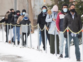 People wear face masks as they wait to be tested for COVID-19 at a clinic in Montreal, Sunday, January 3, 2021, as the COVID-19 pandemic continues in Canada and around the world.