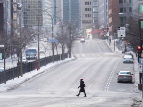 A woman wears a face mask as she crosses Rene-Levesque boulevard in Montreal, Sunday, January 10, 2021, as the COVID-19 pandemic continues in Canada and around the world. The Quebec government has imposed a lockdown and a curfew to help stop the spread of COVID-19. The curfew begins at 8 p.m. until 5 a.m. and lasting until February 8.