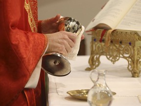 Father Peter Turrone performs Palm Sunday mass and the Eucharist - throughly cleaning the chalice - at the Newman Centre Catholic chapel on St. George St. before an empty church. It is a the beginning of Holy Week leading up to Good Friday and Easter next Sunday on Sunday April 5, 2020.