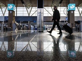 A traveller walks in front of the WestJet check-in aisles at Calgary International Airport on Friday, Jan. 8, 2021.