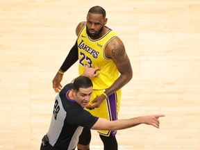 NBA official Mousa Dagher #28 looks over at a fan courtside as he stands in front of LeBron James #23 of the Los Angeles Lakers during the second half against the Atlanta Hawks at State Farm Arena on February 01, 2021 in Atlanta, Georgia.