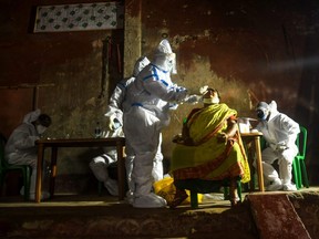 A health worker (C) collects a swab sample from a resident of a containment zone to test for the COVID-19 coronavirus in Kolkata on July 23, 2020.