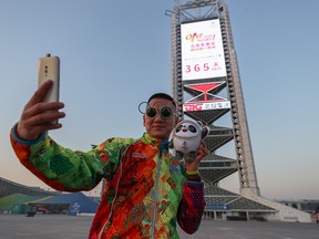 A man takes a selfie on Feb. 4, 2021, in front of a countdown sign for the 2022 Winter Olympics in Beijing, China.