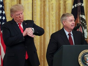 U.S. President Donald Trump checks his watch as Senator Lindsey Graham (R-SC) speaks during an event to celebrate federal judicial confirmations in the East Room of the White House in Washington, U.S., November 6, 2019.