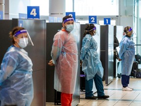 Healthcare workers prepare to test passengers as they arrive at Pearson International airport, after mandatory COVID-19 testing took effect for international arrivals on Feb. 1, 2021.