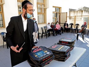People receive pizzas after getting doses of the Pfizer-BioNtech vaccine, at Clalit Health Services in the Israeli city of Bnei Brak, a home to many ultra-Orthodox Jewish residents, near Tel Aviv on February 15, 2021.