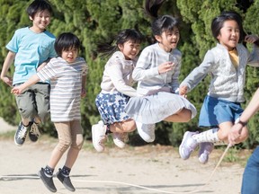Japanese children jump around in a street.