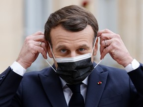 France President Emmanuel Macrson adjusts his face mask before giving a speech on February 4, 2021.