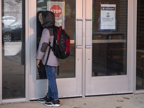 A student peers through the front door of Thorncliffe Park Public School in Toronto on Friday Dec. 4, 2020 after Toronto Public Health closed the school due to a COVID-19 outbreak.
