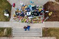 In this aerial photograph from a drone, people look at flowers surrounding a police vehicle as a memorial for slain Boulder Police officer Eric Talley at the Boulder Police Department on March 25, 2021 in Boulder, Colorado. Ten people, including Talley, were killed in a shooting at a King Soopers grocery store on March 22, 2021.