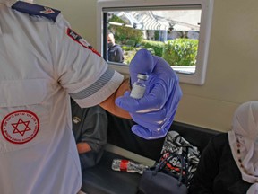 A paramedic with Israel's Magen David Adom medical service shows a vile of the  Pfizer-BioNTech COVID-19 vaccine, before inoculating Palestinians in a mobile clinic at the Damascus Gate in Jerusalem's Old City, on Feb. 26.