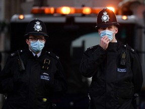 A Metropolitan Police officer adjusts his face mask as he stands on duty outside King Edward VII's Hospital in central London on February 27, 2021.