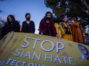 People hold a banner during a candlelight vigil in Garden Grove, California, on March 17, 2021 to unite against the recent spate of violence targeting Asians and to express grief and outrage after a shooting that left eight people dead in Atlanta, Georgia, including at least six Asian women.